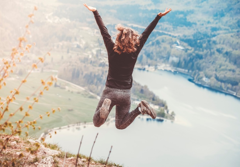 Woman jumping for joy at the top of a mountain